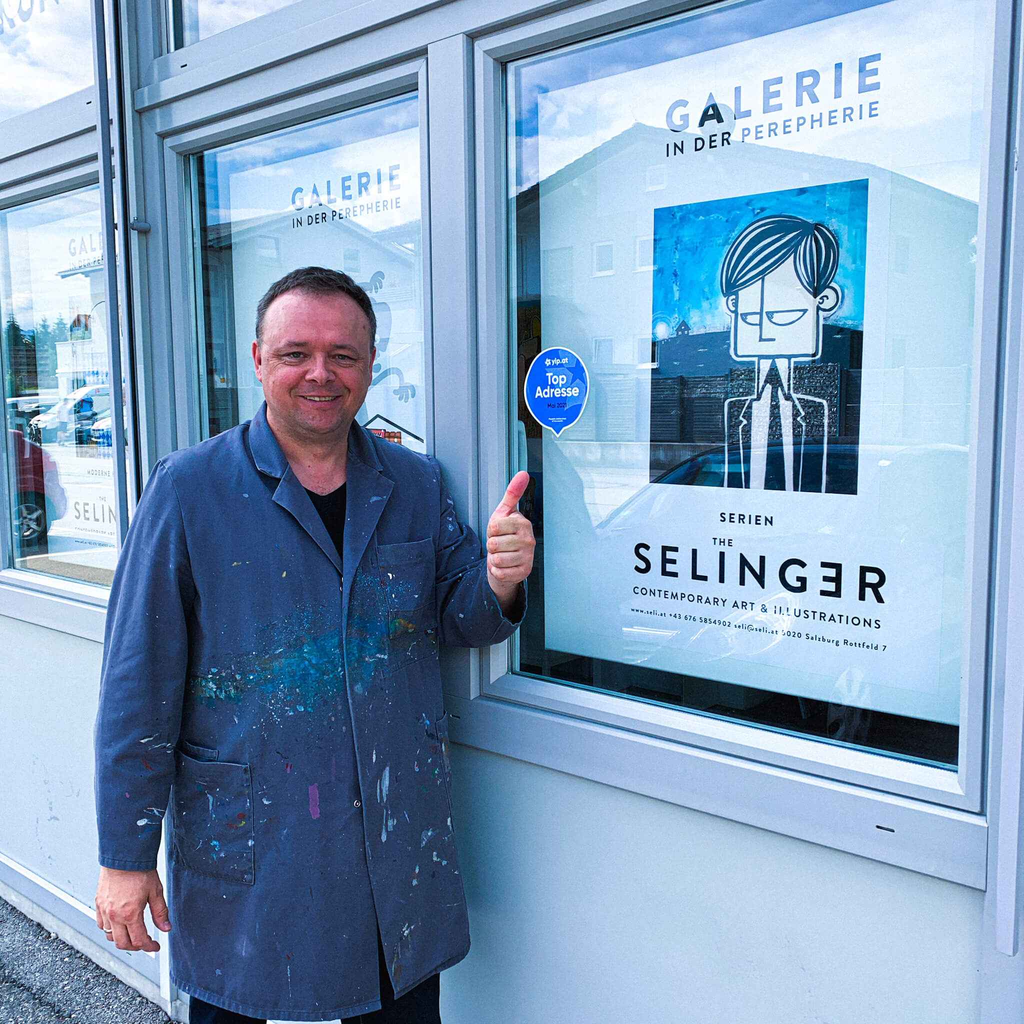 Mann in Malerkittel steht vor Schaufenster einer Galerie
