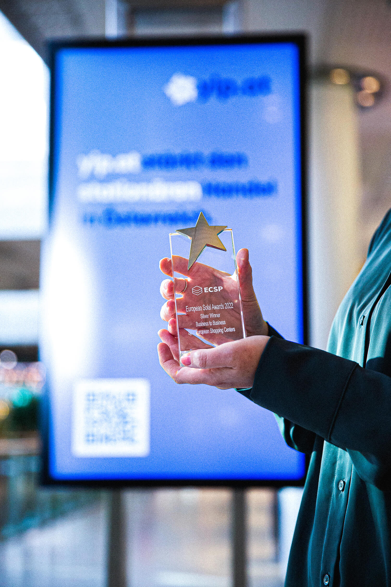 Frau mit grüner Bluse hält European Solal Award 2022 in die Kamera